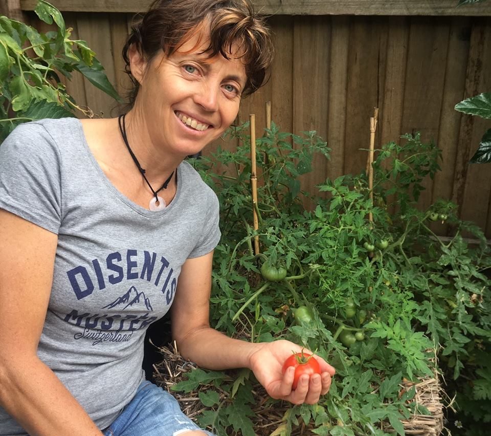 Karen Sutherland holding a ripe Silver Fir tomato, grown at Gunyah garden located in Pascoe Vale South